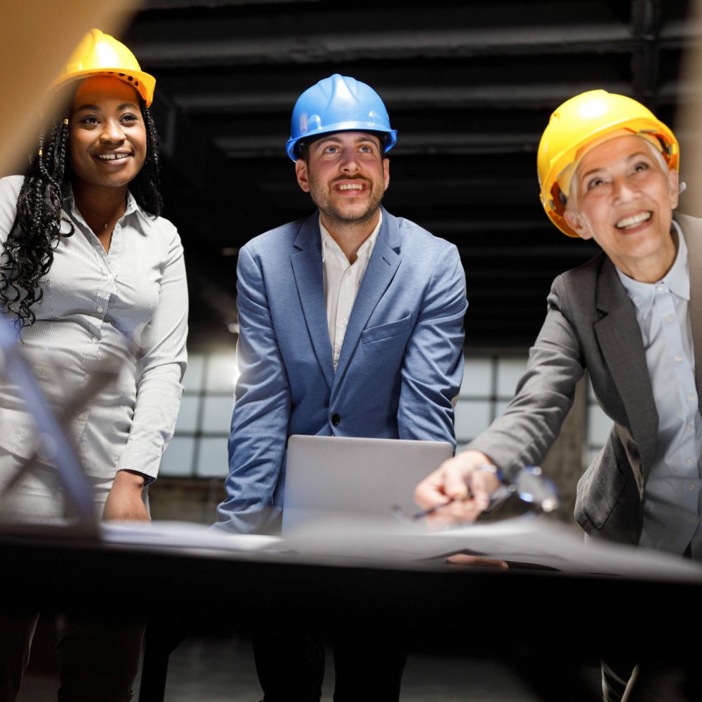 Group of happy building contractors communicating while examining blueprints in the office.